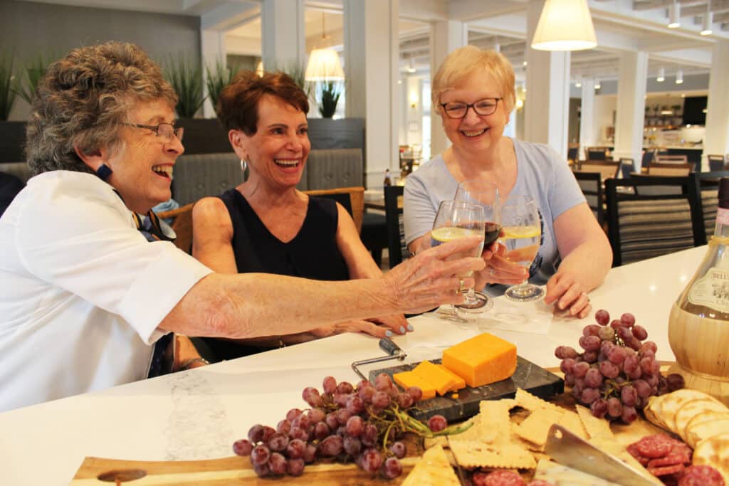 Three residents toasting over a cheese board