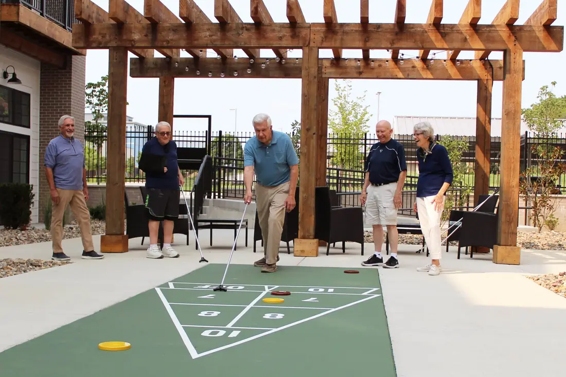 Residents playing shuffleboard under the pergola at Novel Place